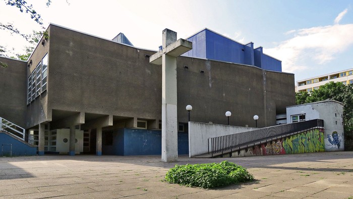 Das Bild zeigt ein modernes Gebäude mit Betonwänden und blauen Akzenten.