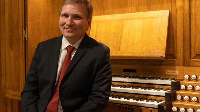Mand i mørkt kostume står ved et orgel