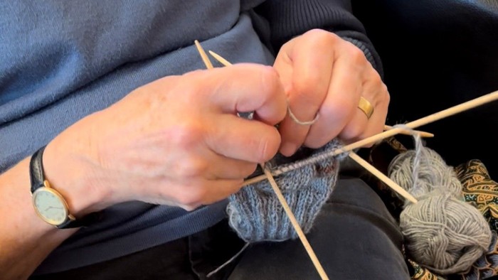 En person sitter og stråler en blå strå.