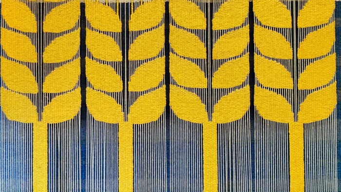 Gul og blå tekstil med stiliserede blade og linierede mønstre