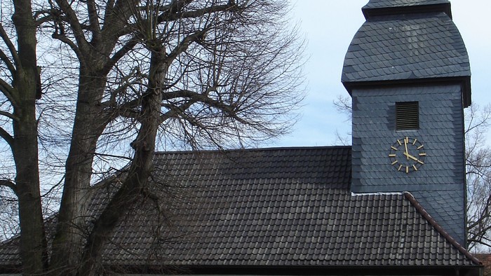 Kleine weiße Kirche mit roter Umrandung und Kirchturmspitze.