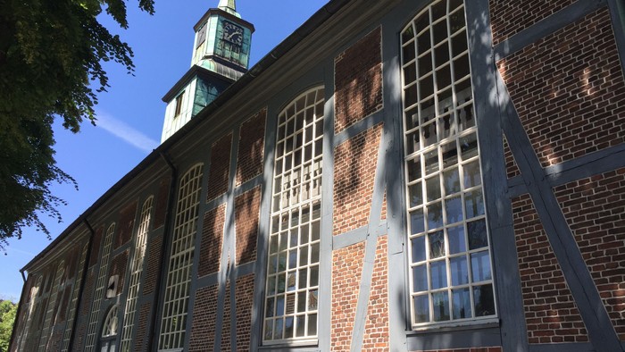Historisches Backsteingebäude mit hohen Bogenfenstern und einem markanten Uhrturm.
