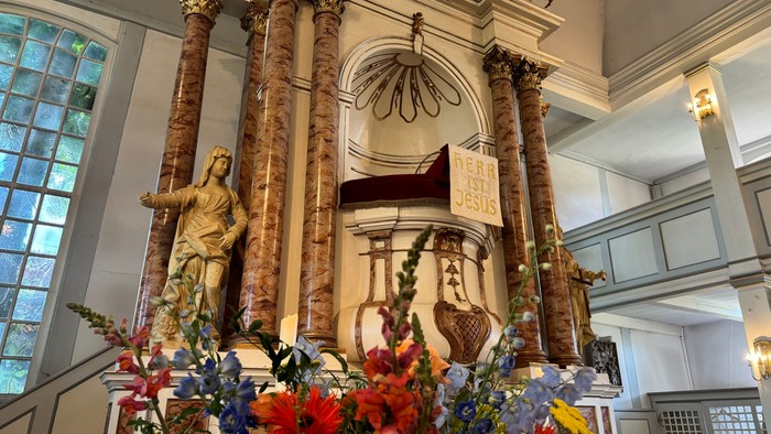 Eleganter Altar, geschmückt mit Statuen, verzierten Säulen und üppigen Blumenarrangements in einem prächtigen Kircheninnenraum.