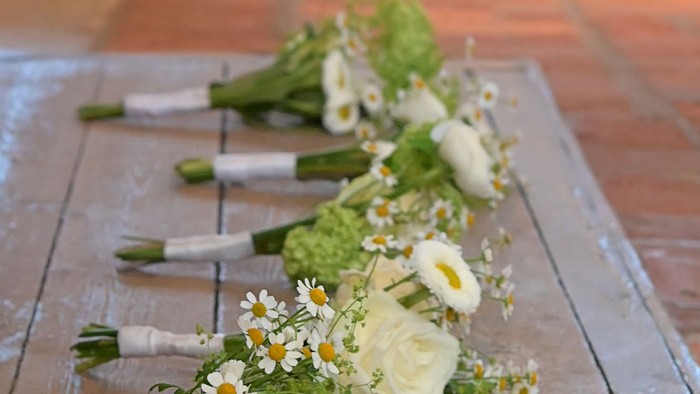 Elegante Blumensträuße aufgereiht auf hölzernen Kirchenbänken während einer Zeremonie.
