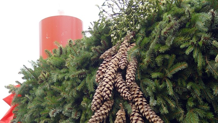 Weihnachtskranz mit Zapfen und roter Schleife.