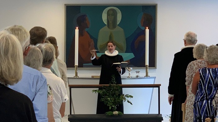 En præst taler til en samling af mennesker i en kirke.