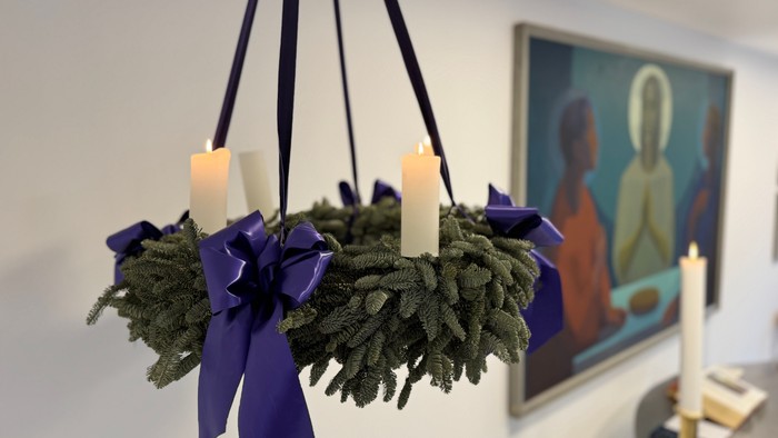 En hængende kranse med tre lysende lygter og violette bänder, placeret foran et maleri.