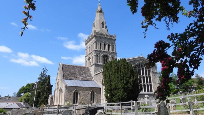 Church with tall spire and graveyard, framed by tree branches