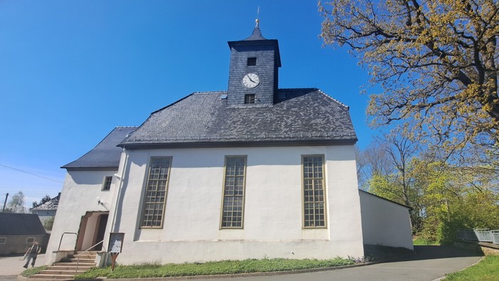 Weißes Kirchlein mit Uhrturm unter blauem Himmel