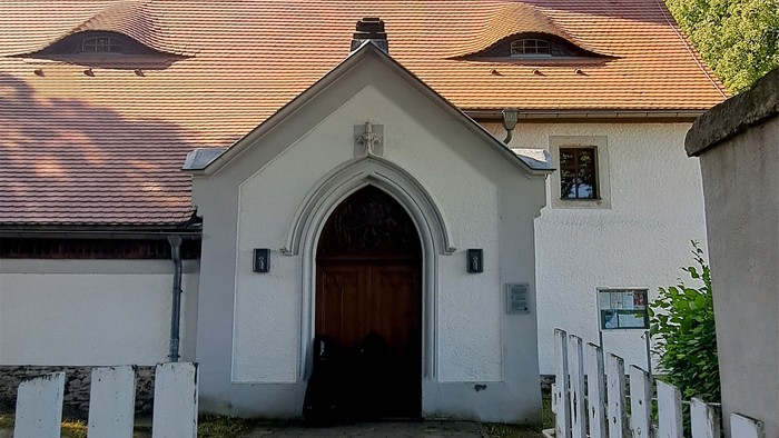 Kirche Kleinschirma mit hohem Turm und rotem Dach, umgeben von Bäumen