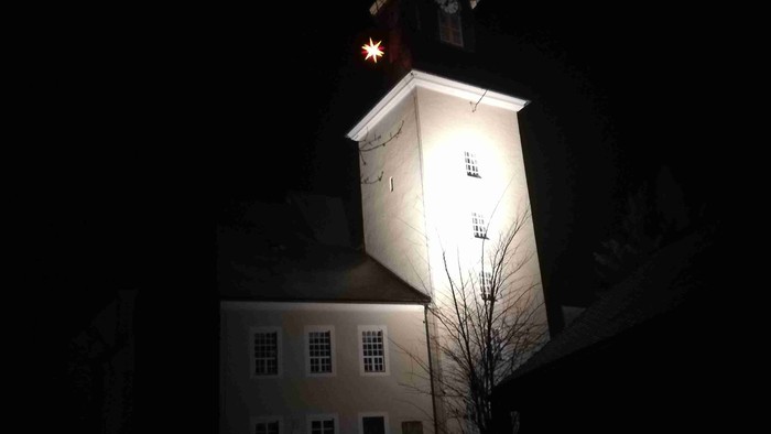 Beleuchteter Kirchturm bei Nacht mit Sternenhimmel