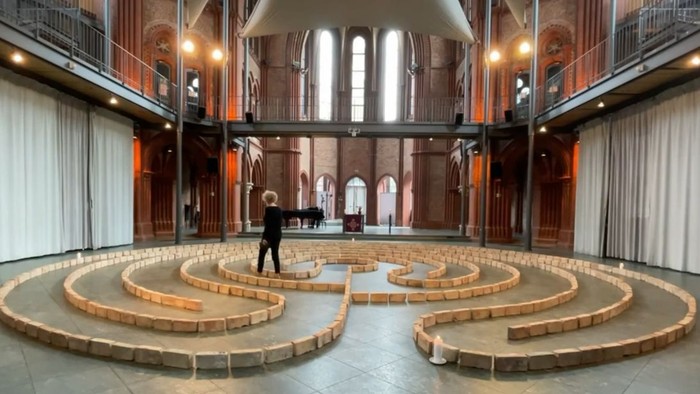 Person steht in einem Labyrinth vor einer großen Fensterfront