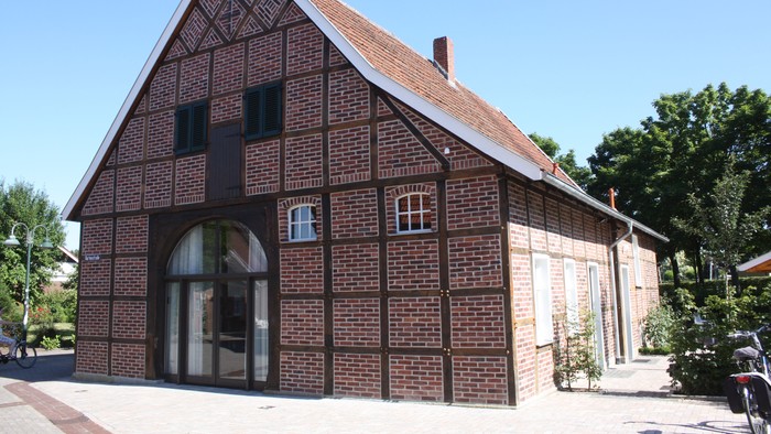Das Bild zeigt ein traditionelles deutsches Haus mit einem steilen Dach und einem großen Torbogen.