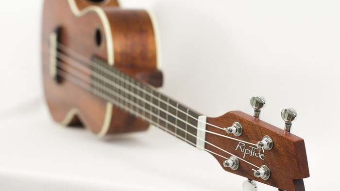 Ein braunes Ukulele mit vier Saiten und einem Holzgriffbrett