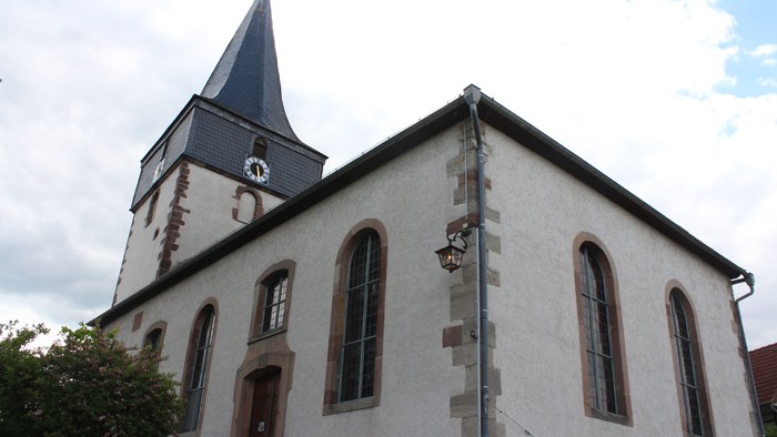 Weiße Kirche mit hohem Turm und Rundbogenfenstern.