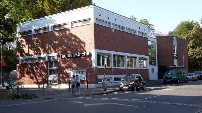 Das Bild zeigt ein modernes Gebäude mit Parkplätzen und Bäumen.