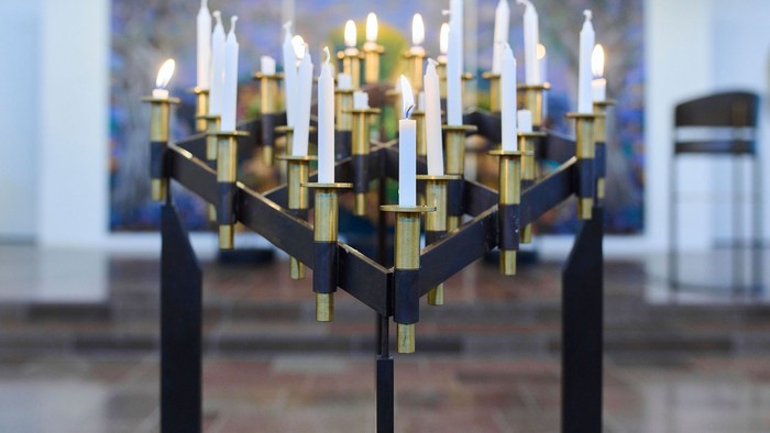 En stor sort kandleholder med guldakcentuer og mange lyse candler.