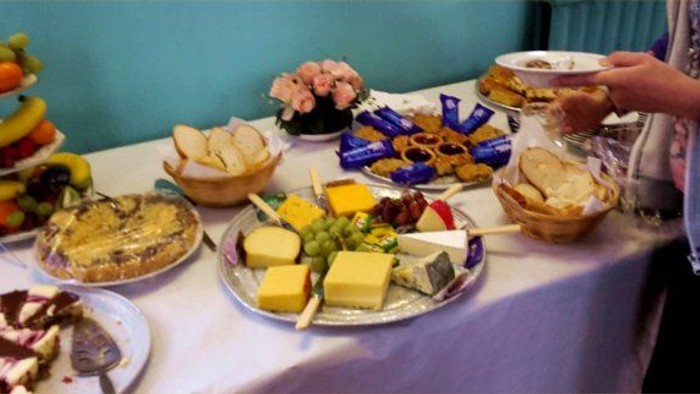 A table with various foods including cheese, crackers, fruits, and desserts