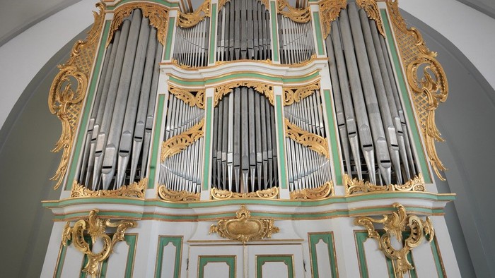 Prachtvolle Kirchenorgel mit goldenen Verzierungen und grün-weißen Akzenten.
