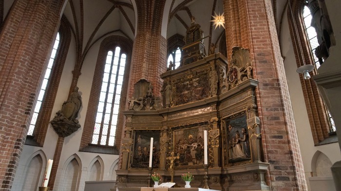 Innenraum einer gotischen Kirche mit Altarraum und hohen Fenstern