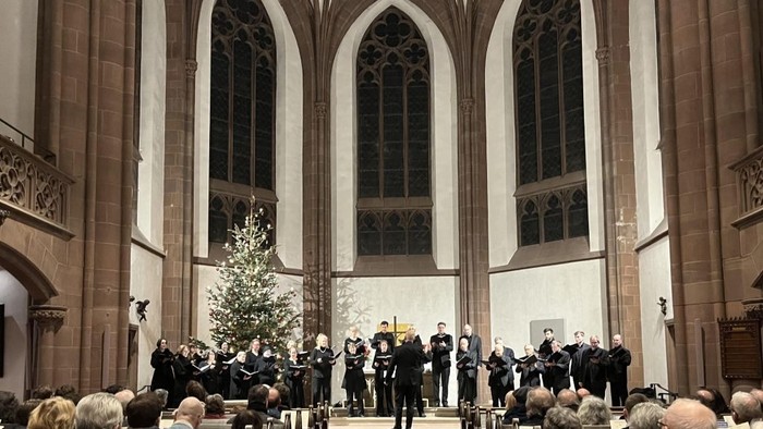 In der Kirche singt ein Chor vor einem Weihnachtsbaum