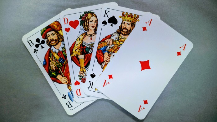 Vier Spielkarten mit Königen und Assen auf grauer Oberfläche