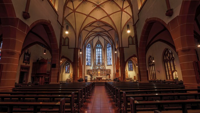 Innenraum einer Kirche mit hohen Gewölben und Kirchenbänken