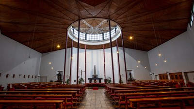 Leere Kirche mit Holzbänken und großem Rundfenster