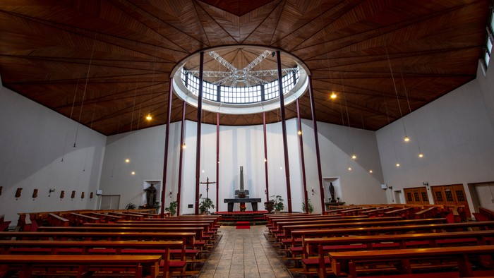 Leere Kirche mit Holzbänken und großem Rundfenster