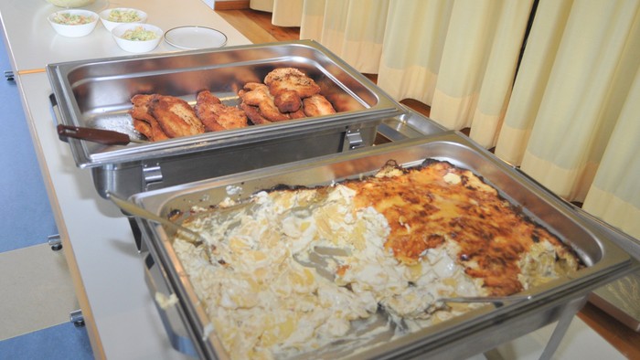 Das Bild zeigt ein Buffet mit verschiedenen warmen Gerichten in Edelstahlschalen