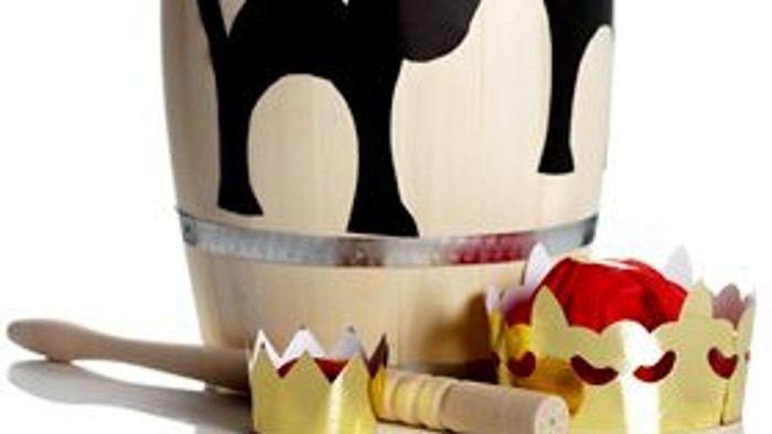 En hvidt og sort kattefigur på en hvidt fat og en kronet kage med en kakebor.