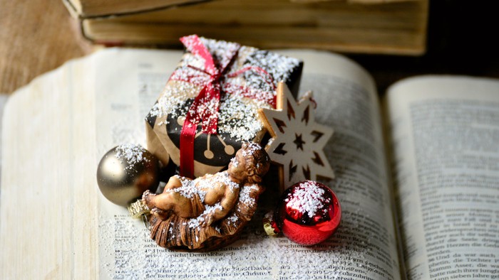 Julepynt og en lille gave anbragt på en åben bog.