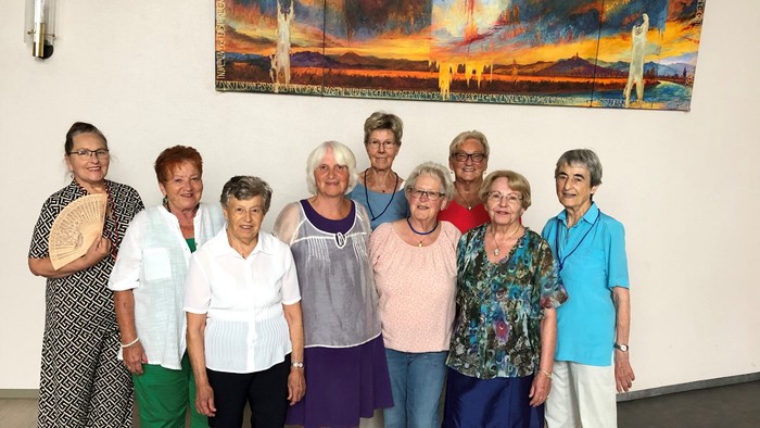 Gruppe von Personen, die vor einem Gemälde posieren.