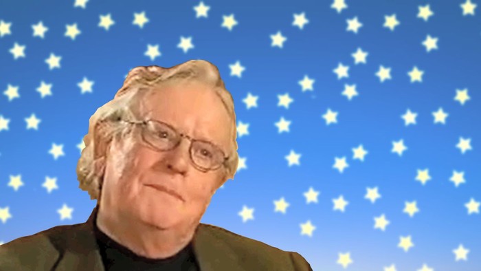 En ældre mand med briller og grå hår står for et blåt skyer med stjerner.