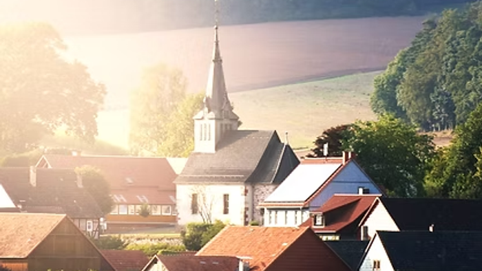 Sonnenuntergang über einem malerischen Dorf mit Kirche und See