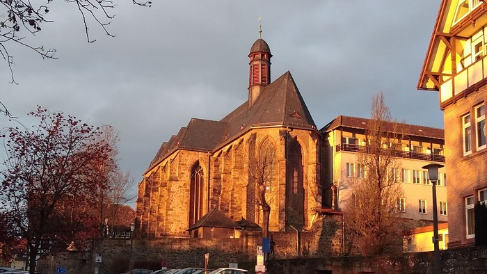 Kirche mit hohem Turm neben einer Straße.