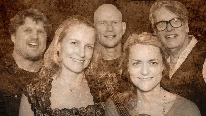 En gruppe af fem mennesker poserer sammen, en af dem holder en guitar