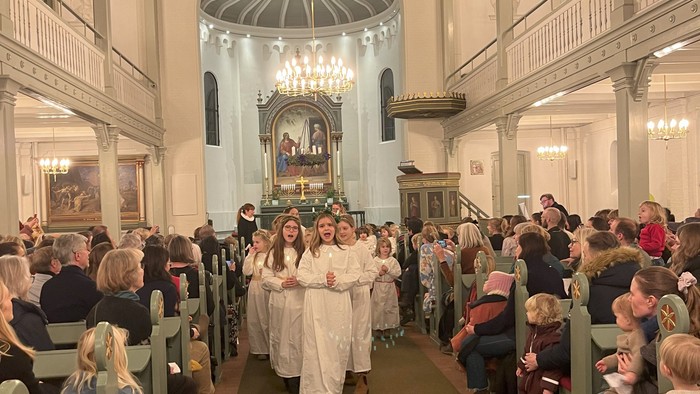 Kirke med mennesker, der sidder i kirkebænke.