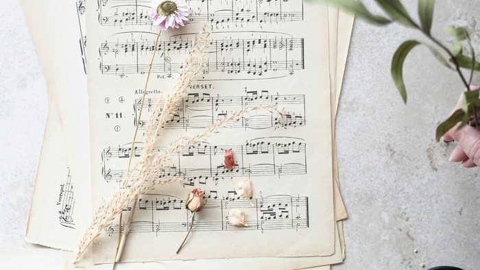 Notenblätter, Schere und Blumen auf weißem Hintergrund