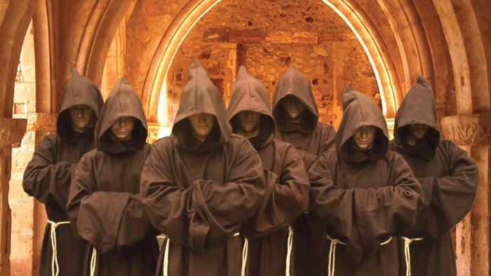 Eine Gruppe von Mönchen in braunen Kutten steht in einer Kirche