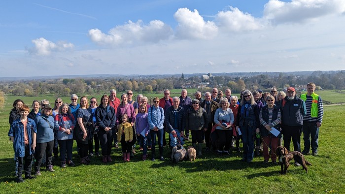 Group of people and dogs posing outdoors on a sunny day