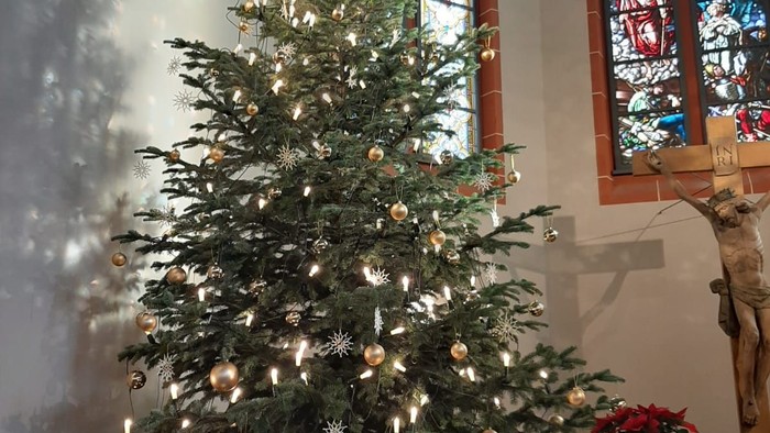 Weihnachtsbaum in der Kirche mit Lichtern und Kugeln