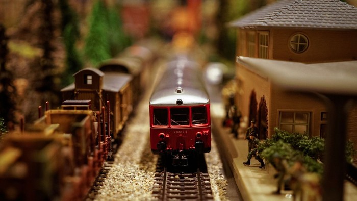 Ein Miniaturmodell einer Eisenbahn mit Personenwagen und Gebäude.