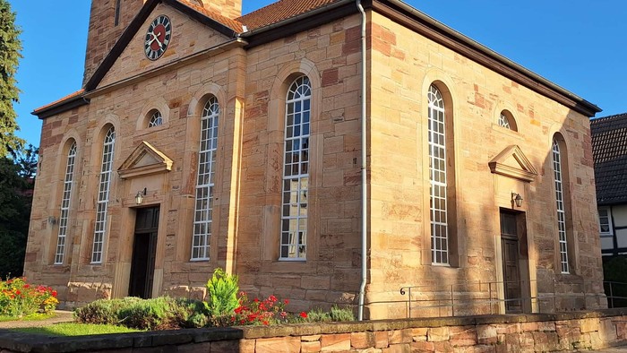 Steinerne Kirche mit hohem Turm und Bogenfenstern.