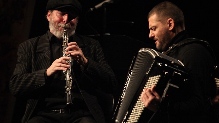 To mænd spiller musik på klarinet og akkordeon på scenen