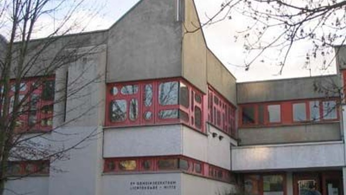 Kirchliches Gebäude mit rotem Zierwerk und Kreuz auf dem Dach