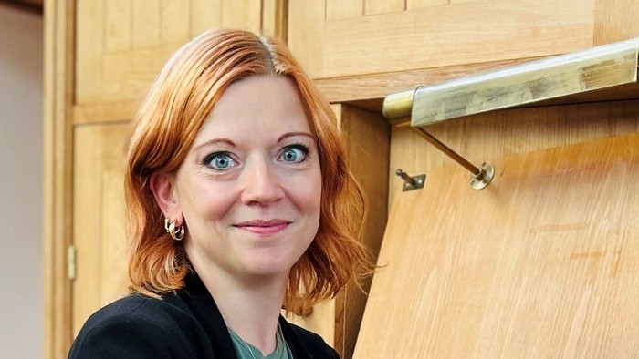En kvinde med rødt hår sidder ved et orgel.