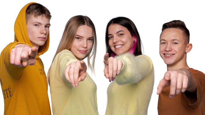 Vier junge Leute, die mit den Fingern auf etwas zeigen und lächeln.