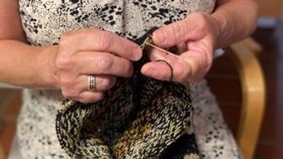 En person sitter og stråler en mørk og lys stråmasket skjorte.