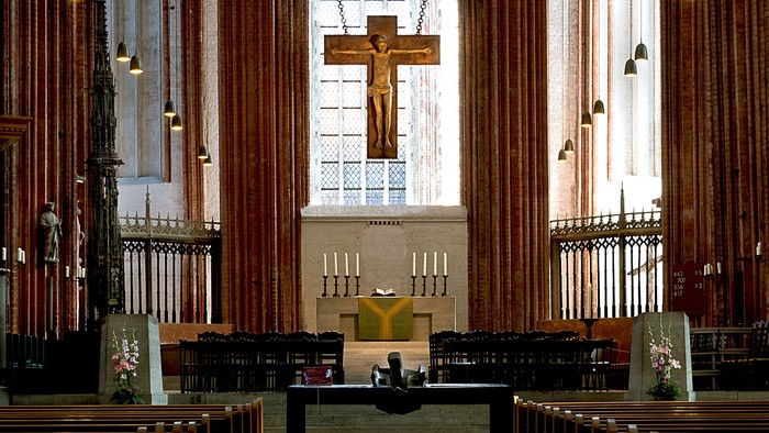 In der Kirche sitzt eine Person vor dem Altar mit Kruzifix.
